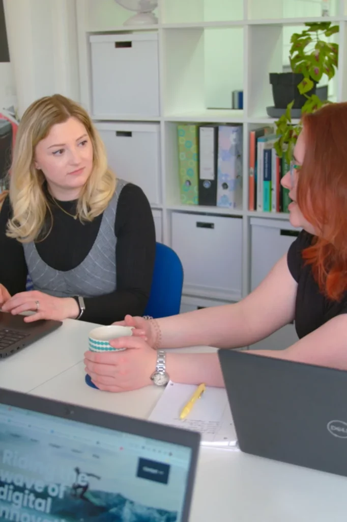 Allie and Lily having a discussion at the meeting table in the britweb office