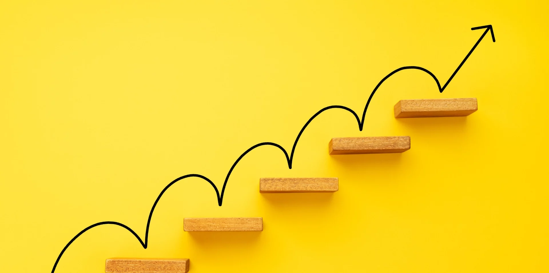 Wooden steps on a yellow background with an up arrow