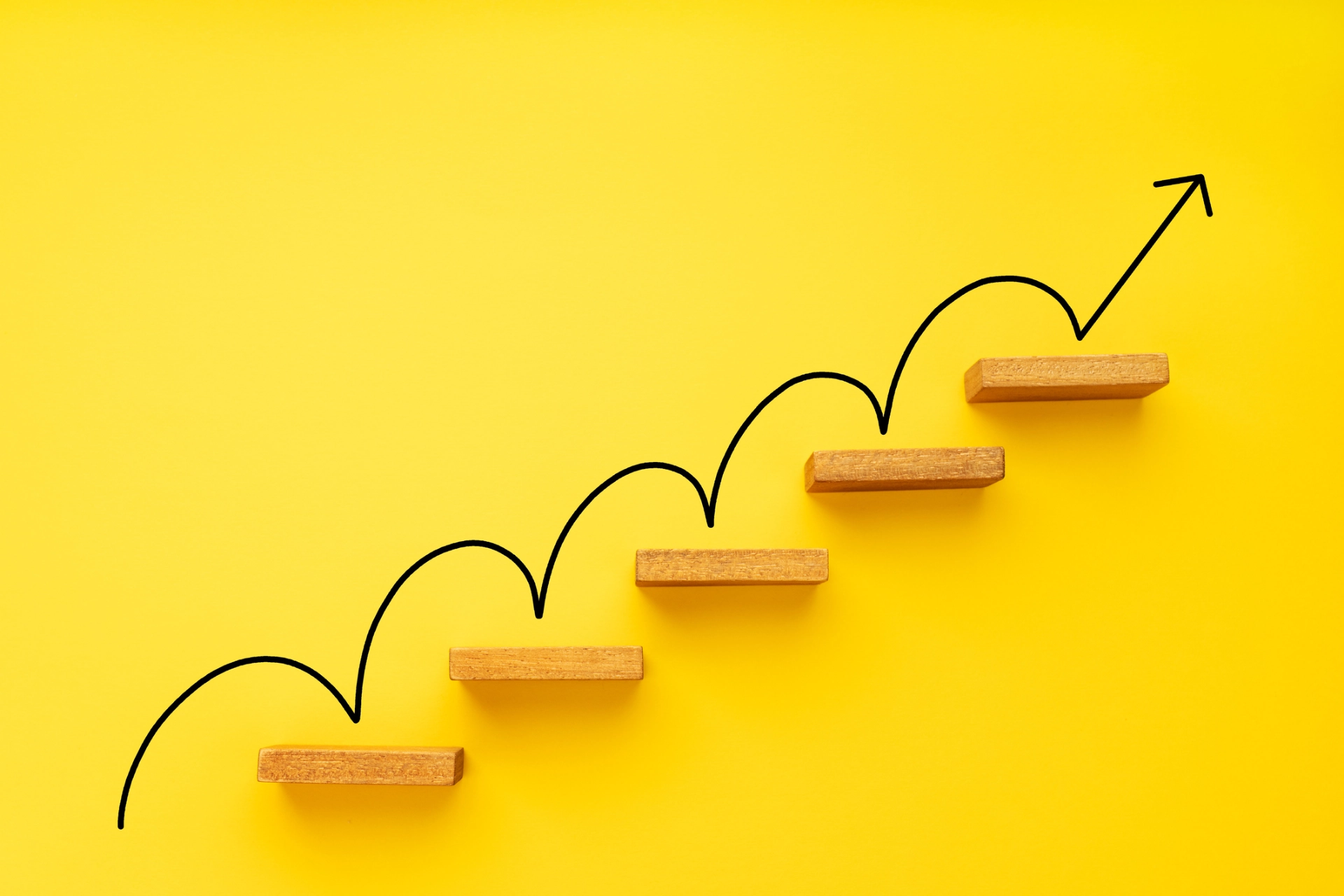 Wooden steps on a yellow background with an up arrow