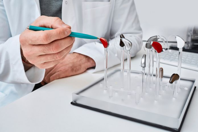 An audiologist points to a display of different hearing aids.