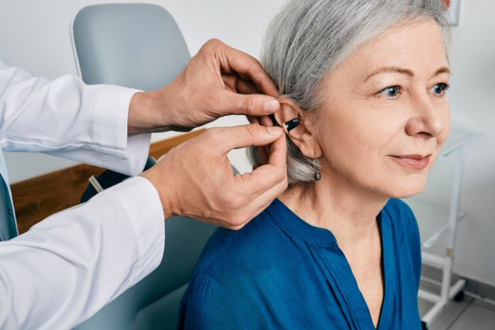 A woman being fitted for a hearing aid by an audiologist.