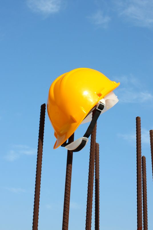 A hard hat hanging from a steel rod on a construction site