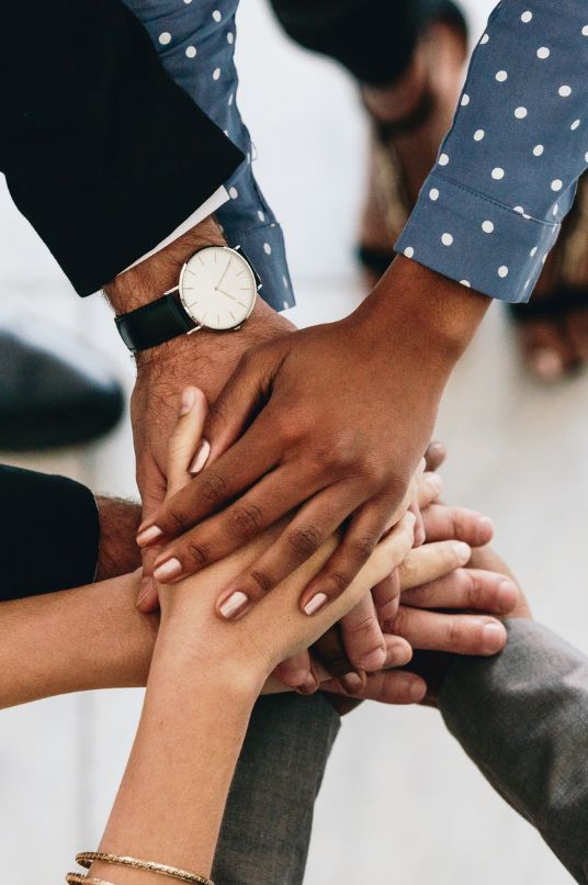 multiple hands together on top of each other